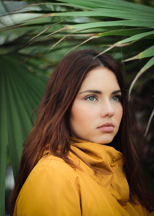 Headshot of Willow wearing a yellow jacket surrounded by palm leaves