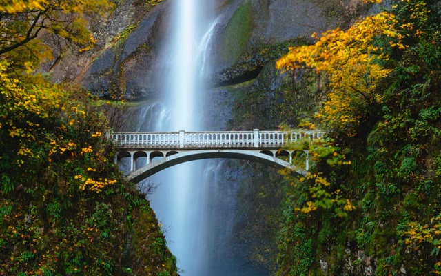 White bridge spanning two cliffs with a waterfall in the background