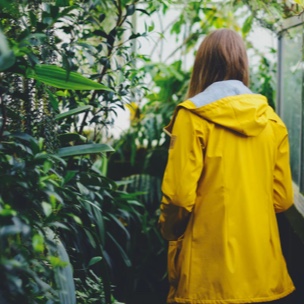 Woman wearing a yellow jacket pictured from behind entering a botanical garden