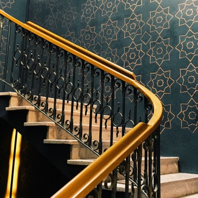 Golden staircase with a patterned wallpaper wall in the background